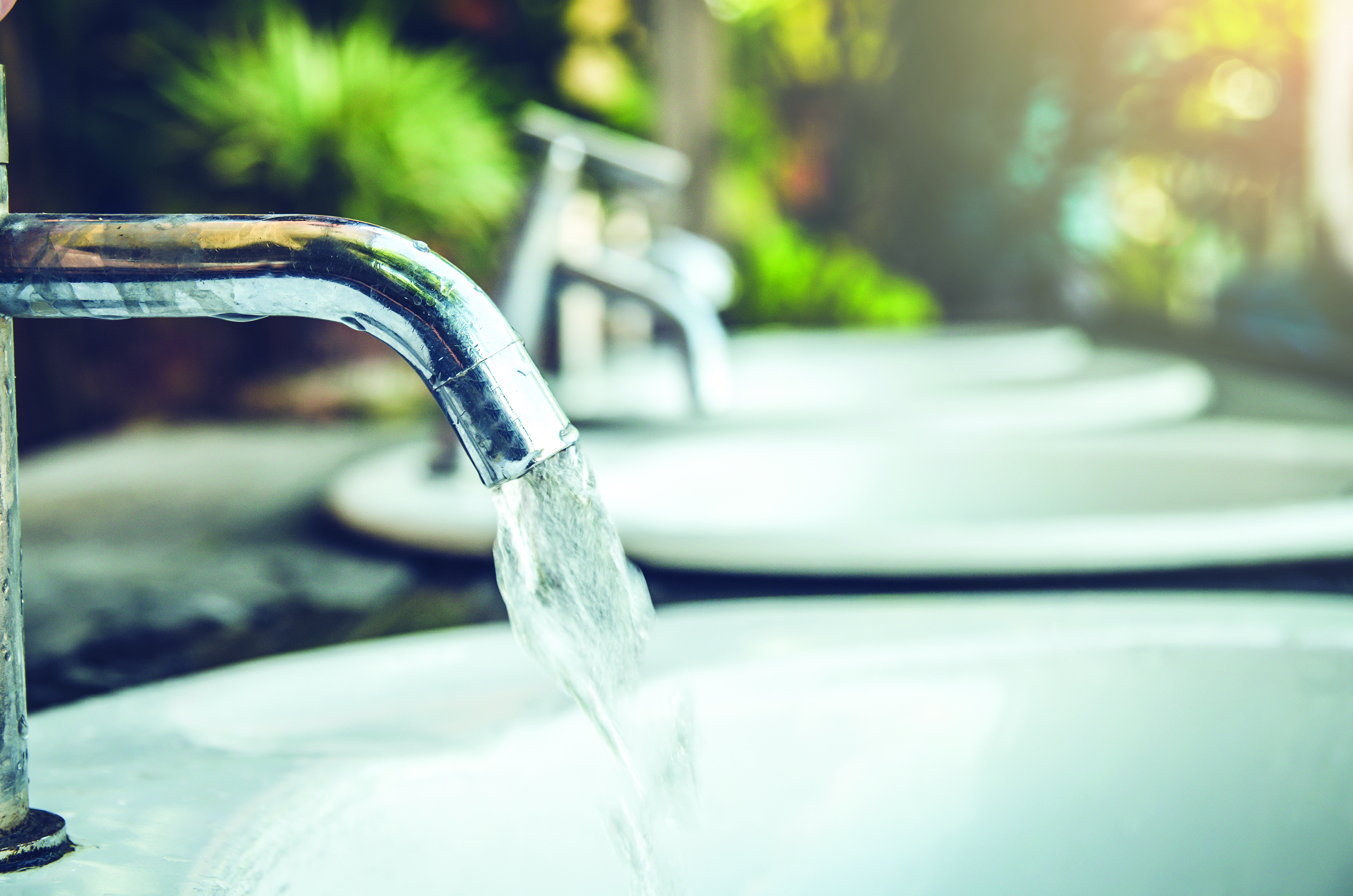A row of chrome faucets with water droplets on them.