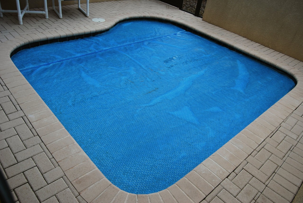 A roughly square pool with a pool cover on. 